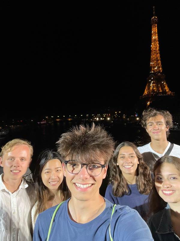 晚上，6名学生在埃菲尔铁塔闪烁的灯光前合影
